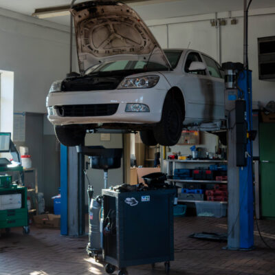 Ein weißes Auto auf einer Hebebühne in einer Werkstatt